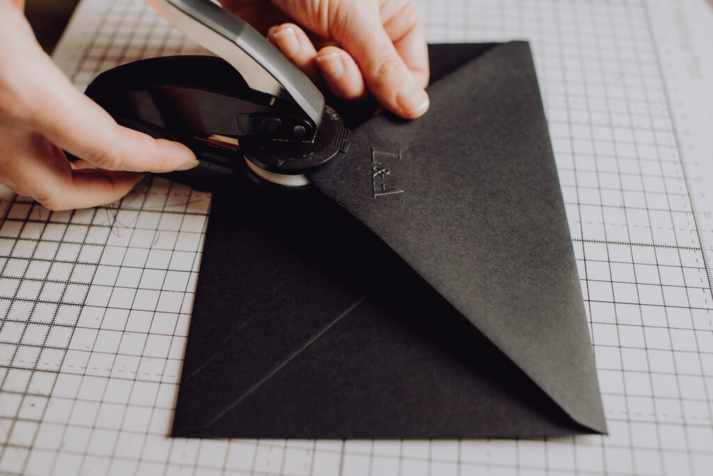 black envelope being embossed by hand